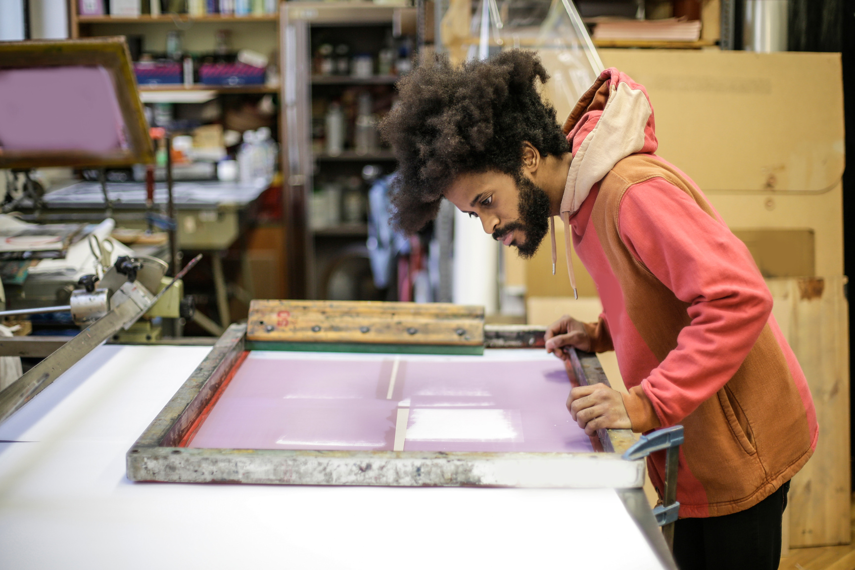 Creative young ethnic craftsman working with screen printing in workshop